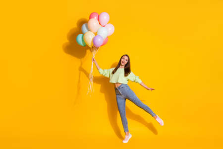 Full size photo of nice carefree playful girl hold many balloons enjoy anniversary celebration wear...