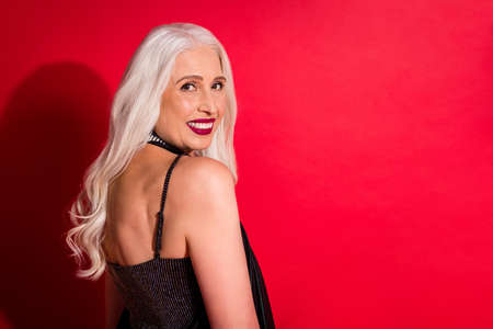 Profile photo of attractive aged grey haired lady luxury look evening makeup posing camera toothy smile photographing wear shine glossy fashion dress isolated red color backgroundの写真素材