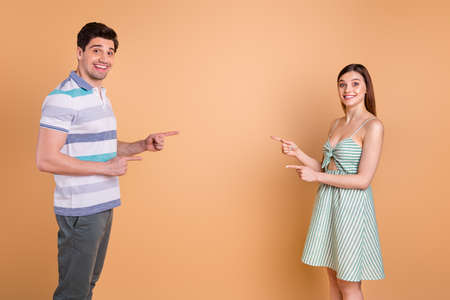 Photo of pretty lady handsome guy couple direct fingers empty space showing novelty sale shopping banner open mouth wear casual summer clothes isolated pastel beige color backgroundの写真素材