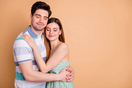 Portrait of passionate married couple man and woman hug embrace cuddle copyspace enjoy togetherness close eyes wear good look skirt isolated over pastel color backgroundの写真素材