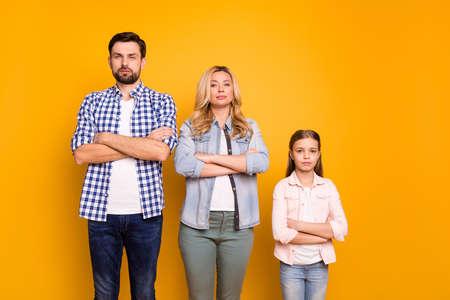 Photo wife beautiful mom lady handsome husband dad guy couple little school girl daughter self-confident competitive family serious look wear casual clothes isolated yellow color backgroundの写真素材