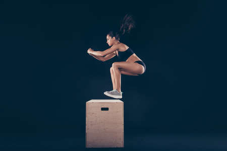 Profile side view of her she nice attractive focused sportive slim thin strong lady doing body sculpt weight loss program isolated over black backgroundの写真素材