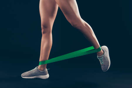 Cropped close-up view of her she nice attractive sportive perfect strong slim thin ladys legs doing work out weight loss isolated over black backgroundの写真素材
