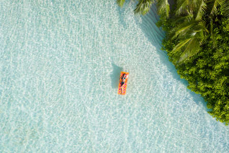 Top above high angle aerial drone view of fit slim attractive girl floating on rubber mattress sea water luxury leisure sunny weather, relax enjoying season mild warm pleasant climate wild forestの写真素材