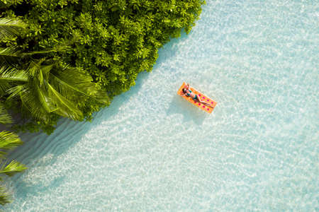Top above high angle aerial drone view of fit slim thin attractive girl floating on rubber mattress clear sea water leisure sunny weather, famous popular direction relax tranquil recreationの写真素材
