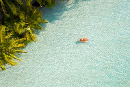 Top above high angle aerial drone view of fit attractive girl floating, lying on rubber mattress...