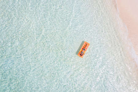 Top above high angle aerial drone view of fit slim tanned attractive girl floating lying on rubber...