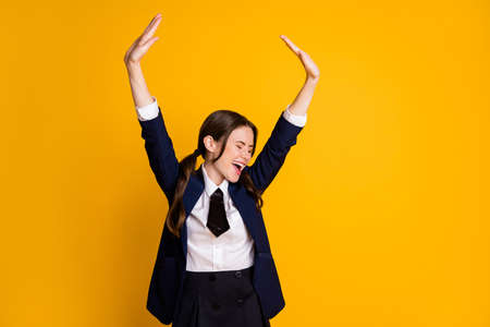 Portrait of her she nice attractive ecstatic cheerful cheery schoolgirl having fun free freedom after classes pass exam rising hands up isolated on bright vivid shine vibrant yellow color backgroundの写真素材