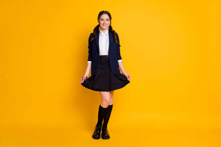Full length photo of positive sweet nice school teenager student touch her skirt enjoy university courses isolated over bright color backgroundの写真素材
