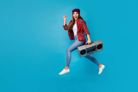 cheery girl jumping carrying boombox having fun isolated over bright vivid shine vibrant blue color backgroundの写真素材