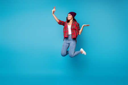 cheerful cheery girl jumping taking making selfie isolated over bright vivid shine vibrant blue color backgroundの写真素材