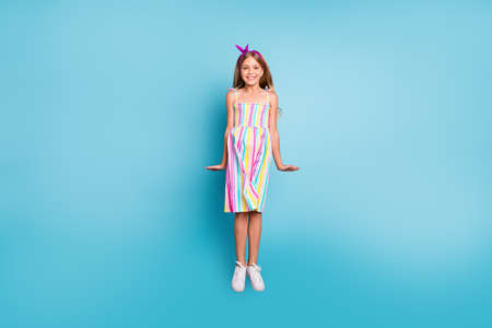 Full length body size view of her she nice-looking attractive lovely pretty cute shy cheerful cheery girl jumping having fun isolated over bright vivid shine vibrant blue color backgroundの写真素材