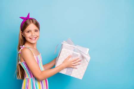 Profile side photo of positive cheerful child girl hold big dotted package gift box give her best...