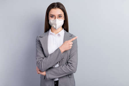 Portrait of her she attractive lady wearing safety n95 mask demonstrating copy empty space blank place mers cov disease sickness illness therapy prevention medicine isolated grey color backgroundの写真素材