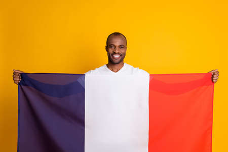 Portrait of positive cheerful afro american guy football fan support national soccer team france on world cup match hold french flag wear white t-shirt isolated over bright shine color backgroundの写真素材