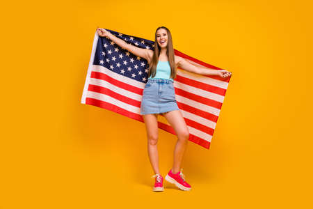 Full length body size view of nice attractive pretty cheerful cheery straight-haired girl holding in hands big united states flag isolated on bright vivid shine vibrant yellow color backgroundの写真素材