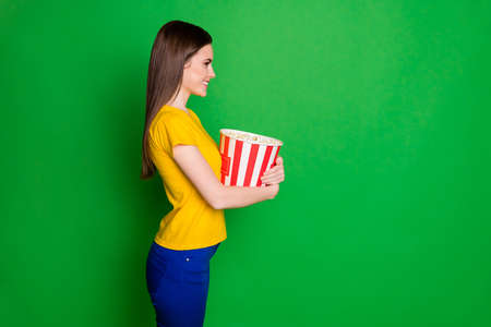 Profile side view portrait of her she nice-looking attractive charming cheerful cheery straight-haired girl holding in hands big corn box isolated on bright vivid shine vibrant green color backgroundの写真素材