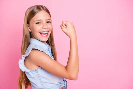 Profile side photo of cheerful ecstatic girl kid demonstrate muscles enjoy corona virus win wear stylish clothes isolated over pastel color backgroundの写真素材