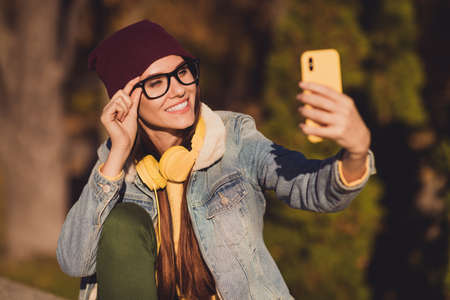 Close-up portrait of her she nice attractive pretty cheerful cheery girl blogger taking making selfie traveling social network blogging touching specs spending sunny day October outdoor outsideの写真素材