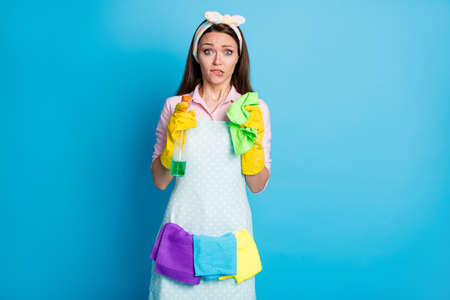 Portrait of her she nice attractive pretty cute worried maid holding in hands tools sanitary hygiene disinfectant biting lip isolated over bright vivid shine vibrant blue color backgroundの写真素材