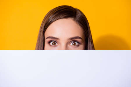 Close-up portrait of her she nice-looking lovely pretty cute funny brown-haired girl hiding face behind copy space place empty blank board isolated bright vivid shine vibrant yellow color backgroundの写真素材