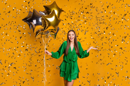 Portrait of her she nice attractive gorgeous cheerful cheery straight-haired girl holding in hand air balls flying decorative elements isolated over bright vivid shine vibrant yellow color backgroundの写真素材