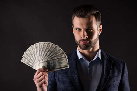 Close-up portrait of his he nice attractive corporate guy banker financier partner holding in hand bunch money fast easy credit service salary win isolated on dark black color backgroundの写真素材