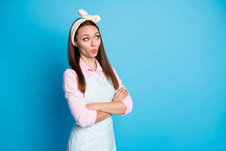 Photo of minded interested girl look copyspace cross hands think thoughts wonder cleaning service work wear pink style stylish trendy shirt isolated over blue color backgroundの写真素材