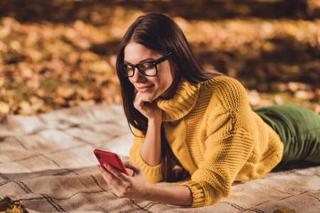 Profile side photo of positive girl rest relax fall forest lawn leaves grass lying checkered plaid...