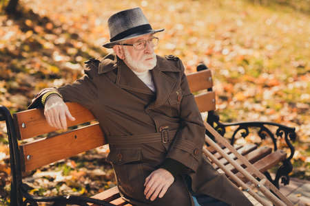 Profile side photo of lonely old man have no friend family sit bench in fall town park with wooden...