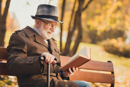 Profile side photo of old man rest relax in city town center yellow color fall park sit bench hold...