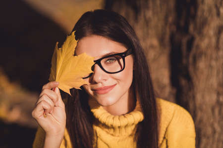Portrait of positive cheerful girl enjoy fall park forest rest relax tree background close cover eye face maple colorful dead leaf wear knitted sweater pulloverの写真素材