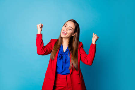Yeah! Photo of attractive professional lady raise arms fists delighted startup successful investment wear luxury red suit blouse shirt isolated blue color backgroundの写真素材
