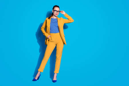 Full length photo of attractive business lady successful worker hold hand vision reading spectacles wear yellow blazer suit dotted blouse shirt isolated bright blue color backgroundの写真素材