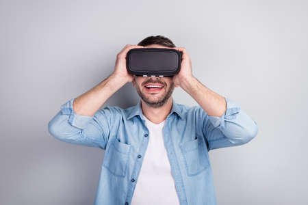 Close-up portrait of his he nice attractive cheerful cheery guy wearing VR helmet headset enjoying...