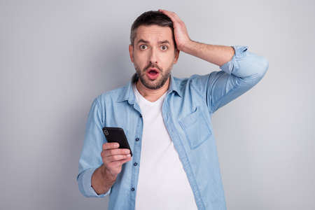 Close-up portrait of his he nice attractive worried nervous guy using digital device browsing reading fake news reaction influencer post isolated over gray light pastel color backgroundの写真素材