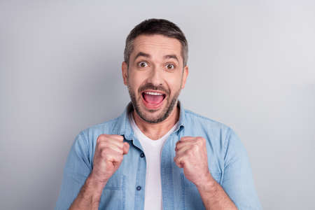 Close-up portrait of his he nice attractive successful cheerful cheery emotional guy celebrating good luck attainment great cool news isolated over gray light pastel color backgroundの写真素材