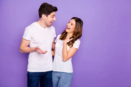 Portrait of positive cheerful fellows couple man tell girlfriend funny joke she laugh touch hand chest wear white casual outfit denim jeans isolated over violet color backgroundの写真素材
