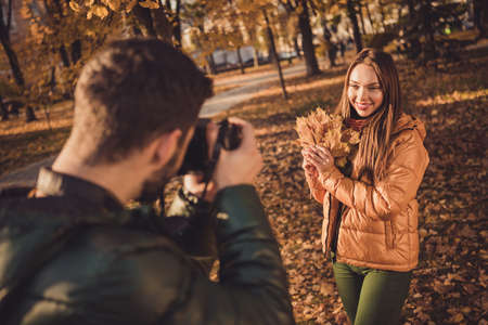 Photo of young guy taking photo digital camera his beautiful girl hold maple leaves in fall...