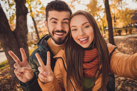 Portrait of positive two people students couple take selfie make v-sign symbol show tongue out in...