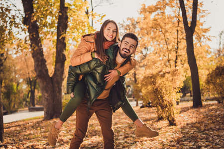 Photo of charming passionate romantic couple in autumn september park guy hold piggyback his...