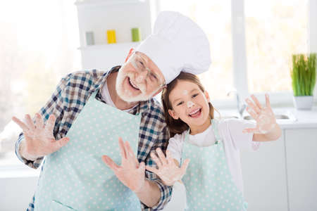 Photo of little funny girl granddaughter help aged chef grandpa forming dough baking cookies together arms covered flavour playful good mood weekend home kitchen indoorsの写真素材
