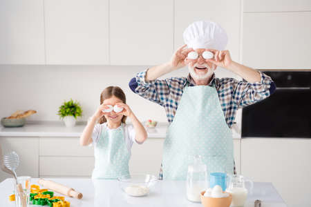 Portrait of nice cheerful kind grey-haired grandparent grandchild cooking homemade domestic dough...