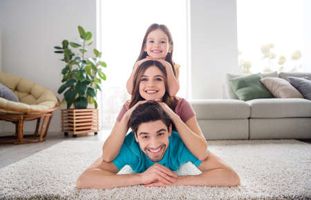 Close up photo of idyllic family three people small kid girl mommy daddy face lie floor enjoy rest relax in house indoorsの写真素材
