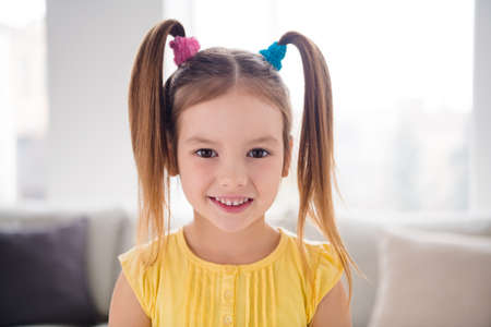 Close up photo of charming lovely little girl kid look in camera toothy smile in living room house...