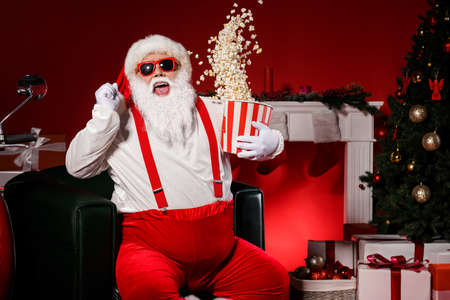 Crazy white grey hair santa claus hold box with air fly pop corn raise fists have x-mas christmas tree holly decoration isolated bright shine color backgroundの写真素材