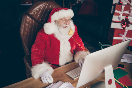 Top above high angle view photo funny grey beard santa claus sit table work computer call telephone...