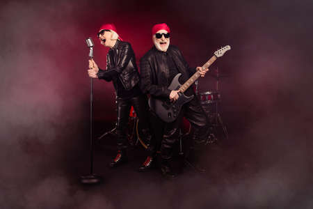 Photo of two aged lady man popular old rock group perform concert play solo guitar sing legend song farewell show career end wear trendy rocker leather outfit isolated black color backgroundの写真素材