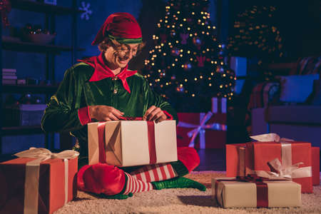Full size photo of funky elf sit floor open x-mas gift box in house indoors with christmas ornament...