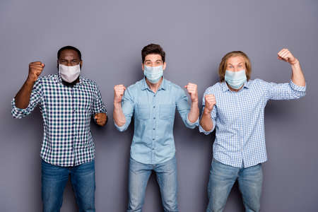 Crazy football fan guys support pals watch football world final cup celebrate team victory in corona virus quarantine wear respiratory mask casual clothes isolated gray color backgroundの写真素材